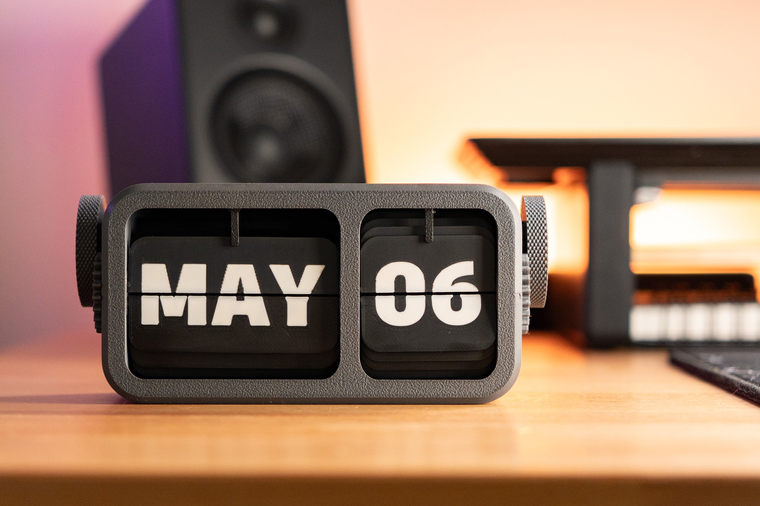 3d printed flip calendar sitting on desk with month and date shown with a gray body and white letters.