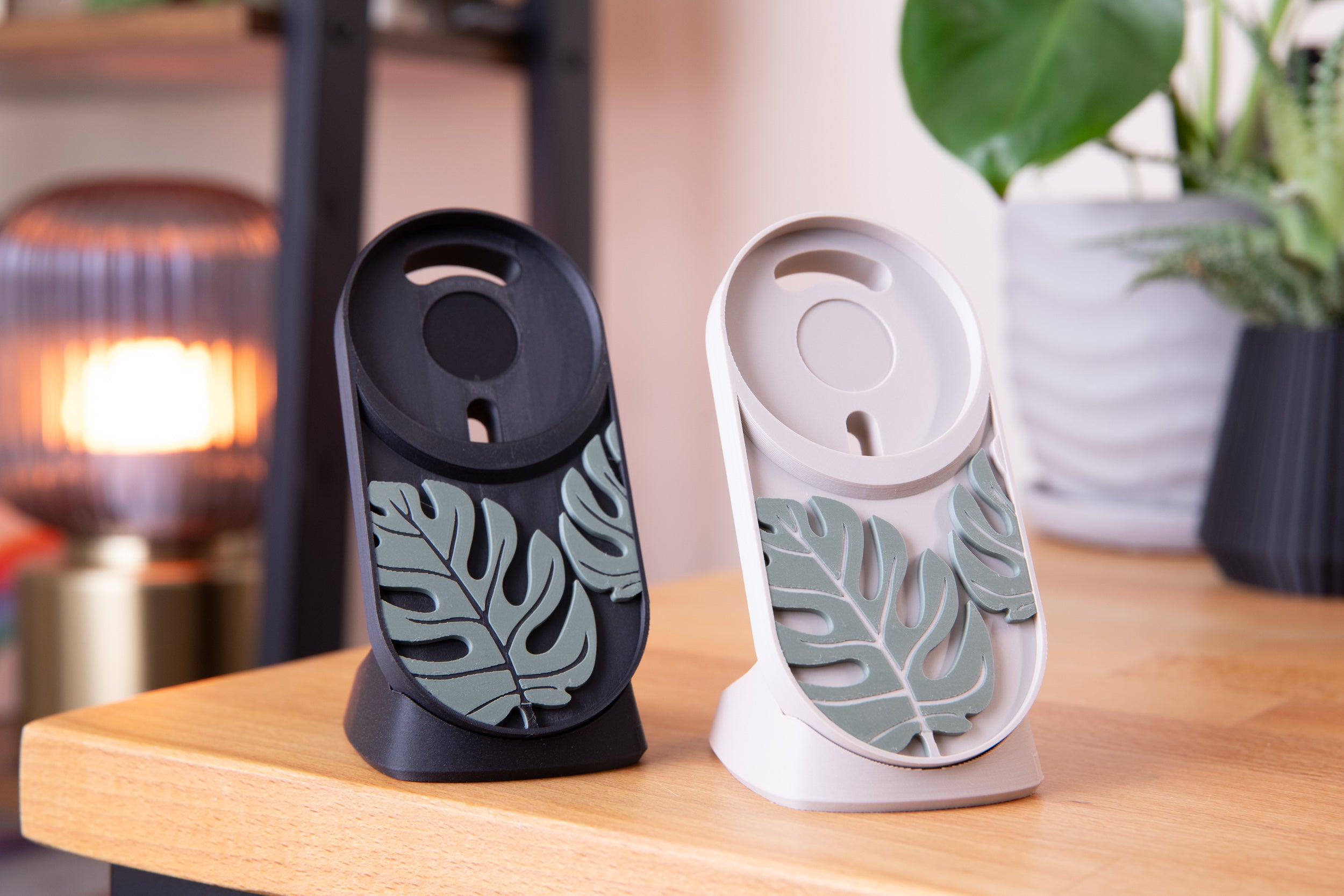 3d printed monsterra magsafe chargers shown in black and beige, sitting on desk. 